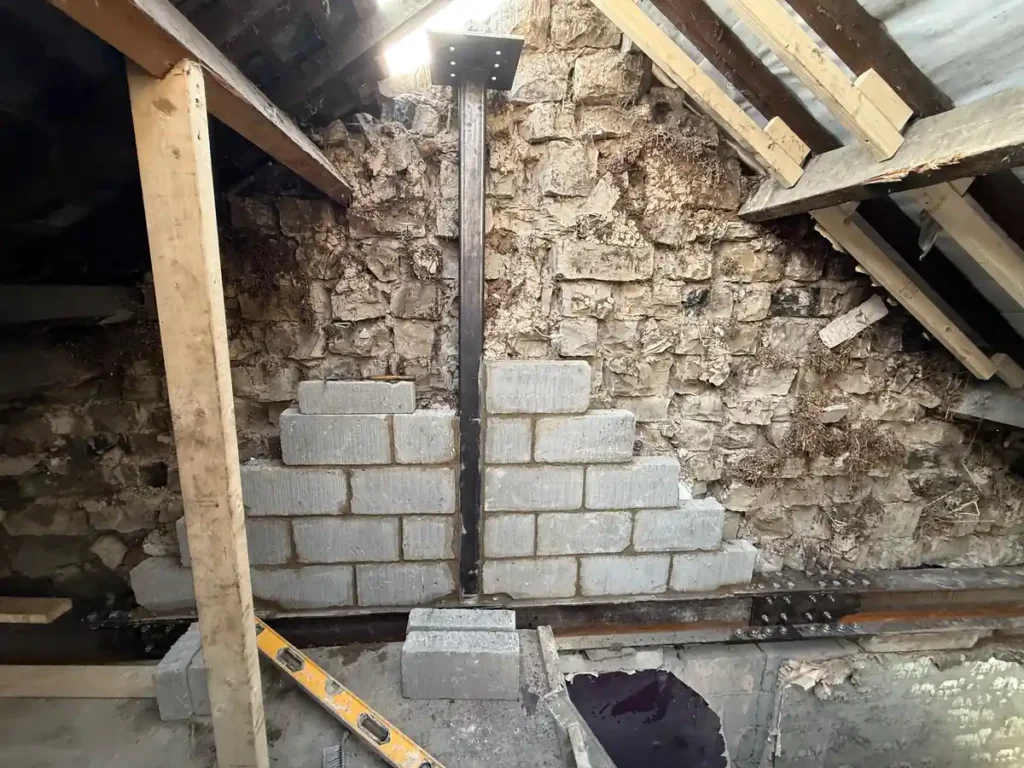 Steel beam and new blockwork installed against the original stone wall during the structural works stage of a loft conversion