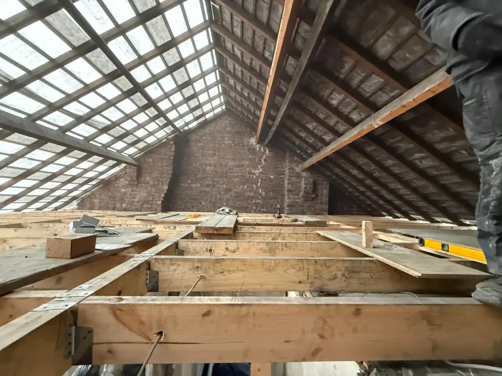 Loft interior stripped back to the original roof timbers and brick gable before a dormer conversion begins
