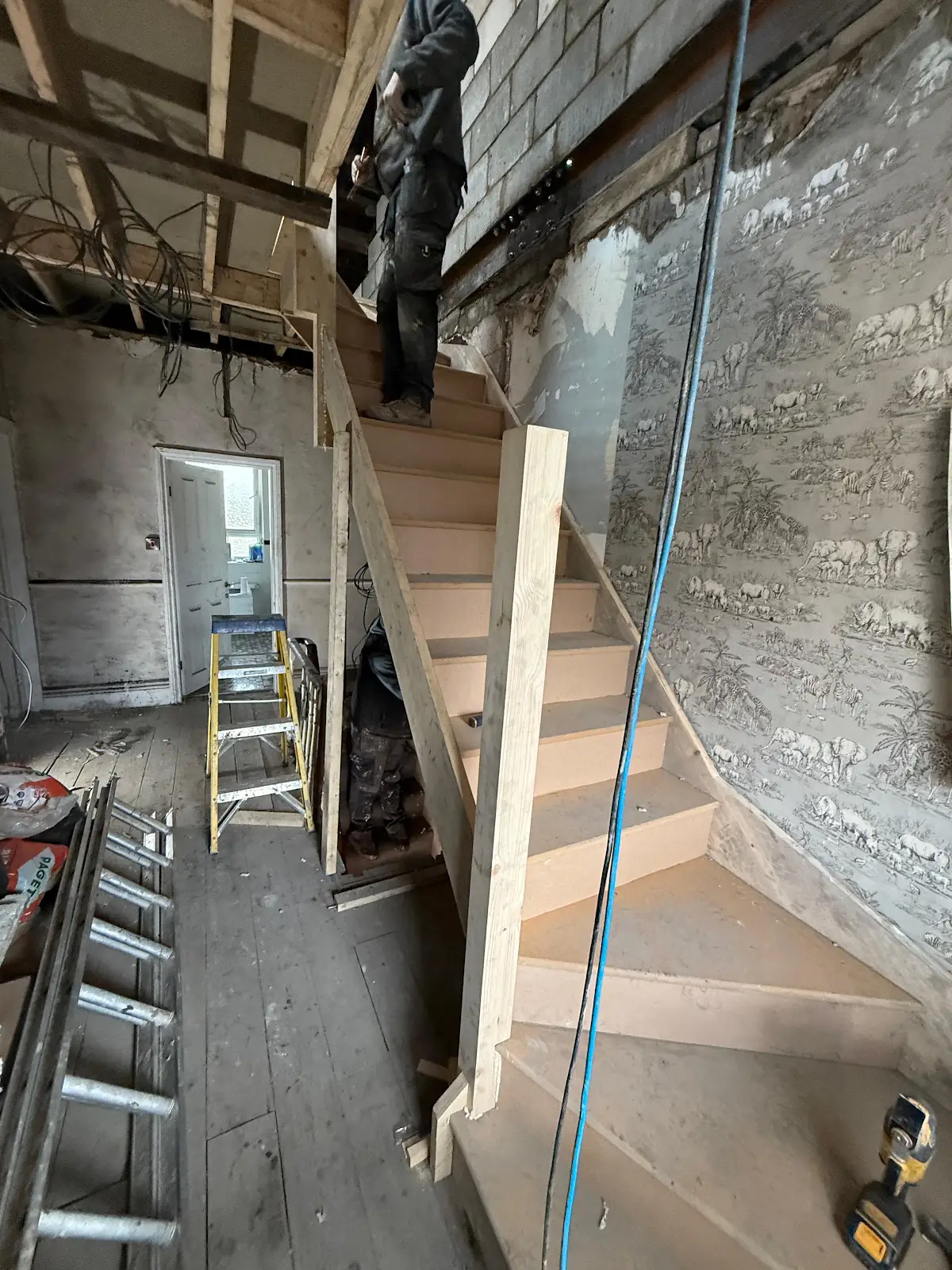 New timber staircase beside unfinished masonry and wall framing