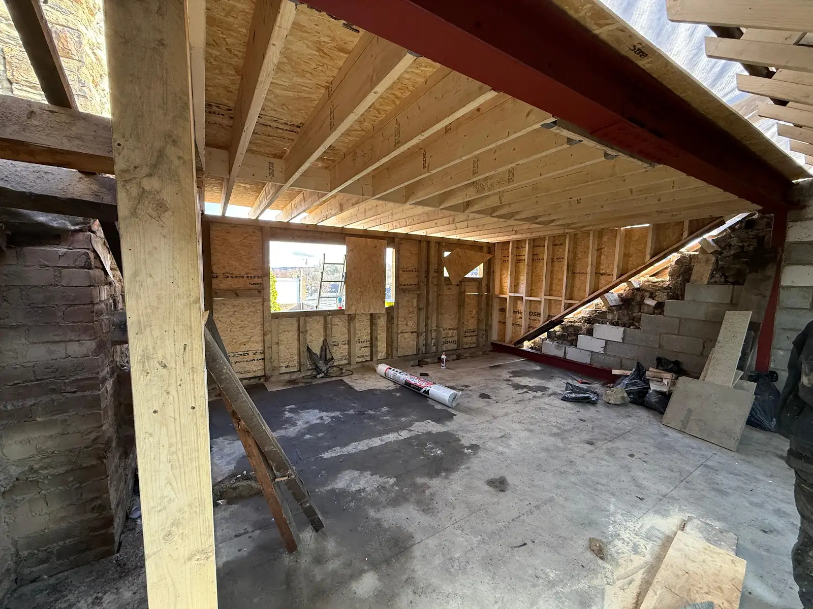 Red structural steel beam beneath timber joists in an unfinished room